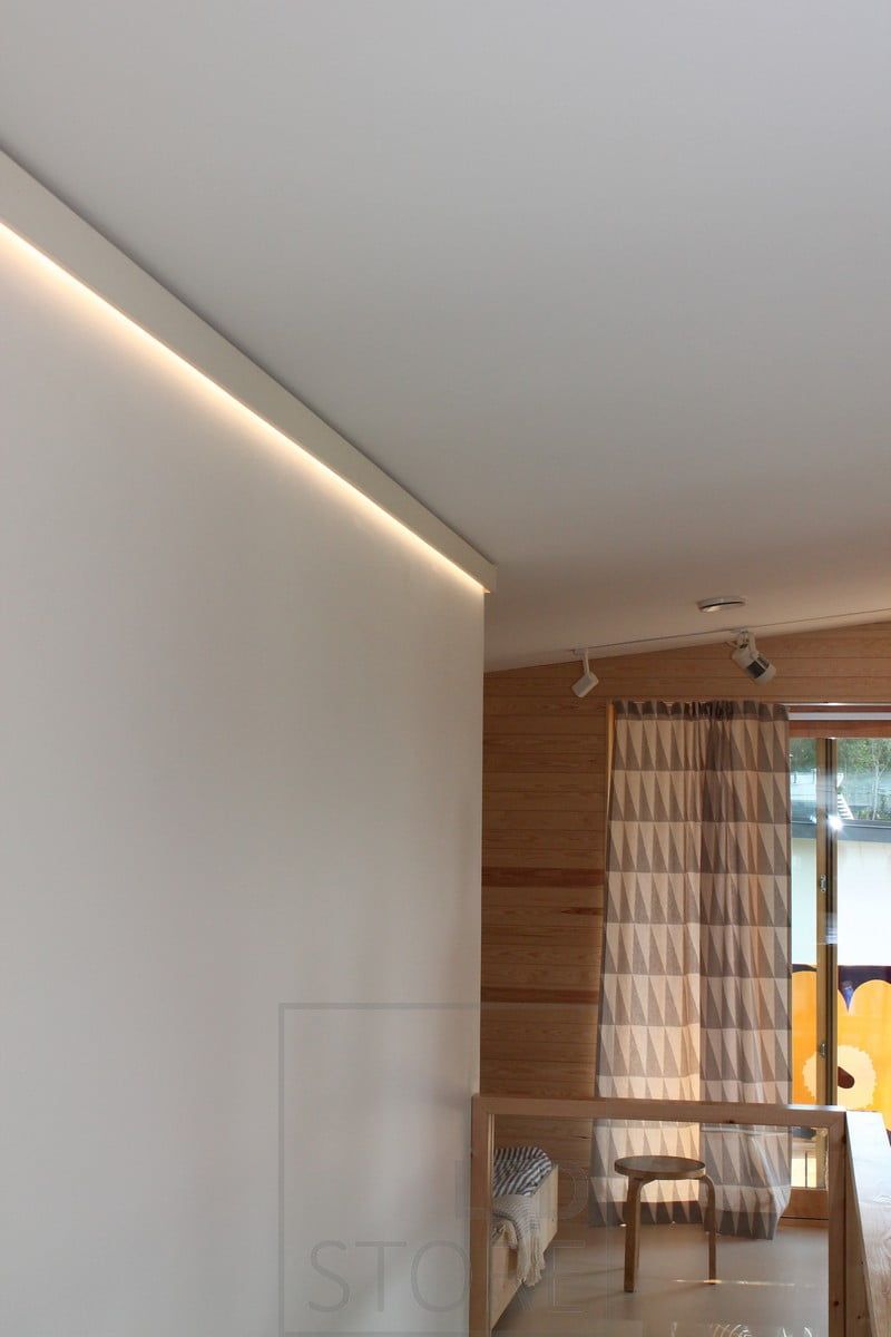 Behind the decorative strip, a wall-illuminated LED strip creates a soft light.